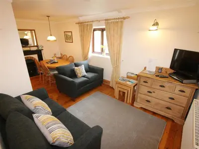 a living room with a couch and a tv and a table at Treveglos Barn on the coast road close to Harlyn Bay and Padstow. in St Merryn