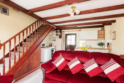 a red couch in a living room with a staircase at Lilliput Mabe far views of the countryside in Budock Water