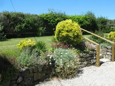 a garden with flowers and a stone wall at Lilliput Mabe far views of the countryside in Budock Water