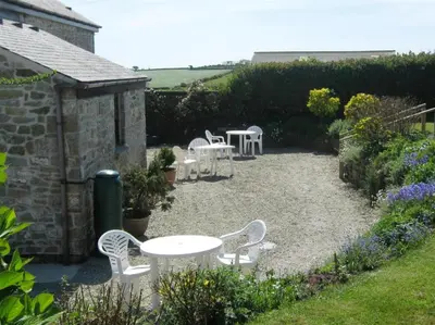 a patio with white tables and chairs in a garden at Lilliput Mabe far views of the countryside in Budock Water