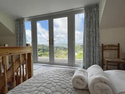 a bedroom with a bed and a large window at Pentref St Just in Roseland with beautiful views in Saint Just in Roseland