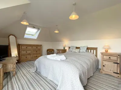 a bedroom with a large bed and a television at Pentref St Just in Roseland with beautiful views in Saint Just in Roseland