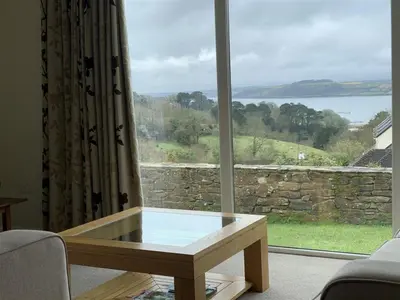 a glass coffee table in front of a large window at Pentref St Just in Roseland with beautiful views in Saint Just in Roseland