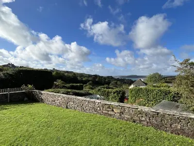 a stone wall in a yard with a green lawn at Pentref St Just in Roseland with beautiful views in Saint Just in Roseland