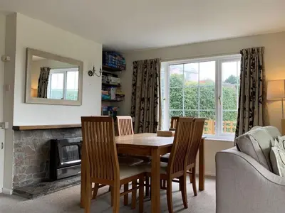 a dining room with a table and chairs and a fireplace at Pentref St Just in Roseland with beautiful views in Saint Just in Roseland