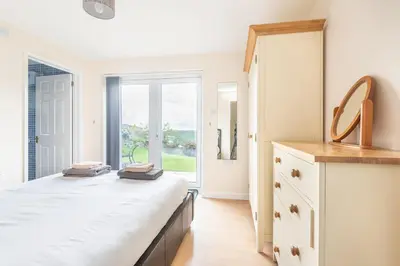 a bedroom with a bed and a large window at Atlantic View Mawgan Porth with sea views in Saint Mawgan