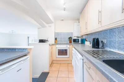 a kitchen with white cabinets and a sink at Atlantic View Mawgan Porth with sea views in Saint Mawgan