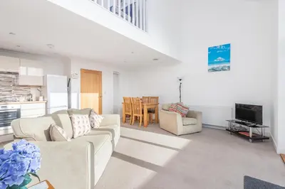 a living room with a couch and a table and a kitchen at Crysawna Newquay close to the beach amenities in Newquay