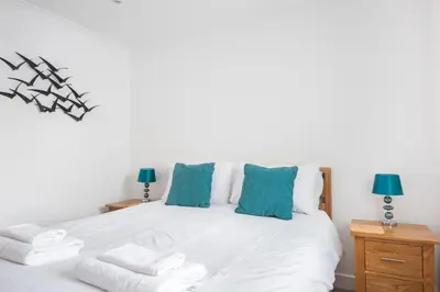 a bedroom with a white bed with blue pillows at Crysawna Newquay close to the beach amenities in Newquay