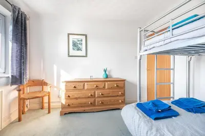 a bedroom with a bunk bed and a wooden dresser at Shellseekers lovely views across Port Isaac in Port Isaac