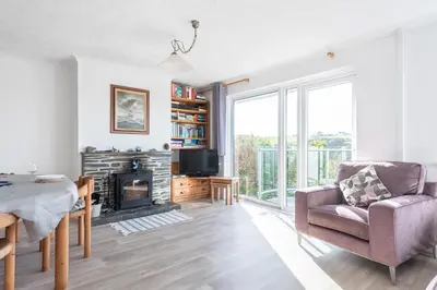 a living room with a fireplace and a chair at Shellseekers lovely views across Port Isaac in Port Isaac