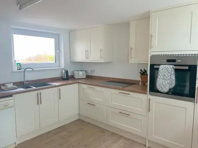 a white kitchen with white cabinets and a window at Shellseekers lovely views across Port Isaac in Port Isaac