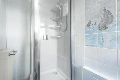 a white bathroom with a shower and a tub at Shellseekers lovely views across Port Isaac in Port Isaac