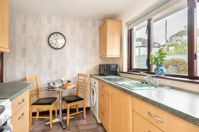 a kitchen with a sink and a table with chairs at Giggles in the heart of bustling town Wadebridge in Wadebridge