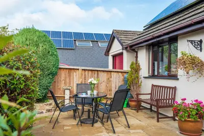 a patio with a table and chairs and solar panels at Giggles in the heart of bustling town Wadebridge in Wadebridge