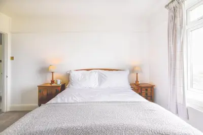 a bedroom with a bed with white sheets and two lamps at Hazeldene amazing sea and countryside views in Crackington Haven