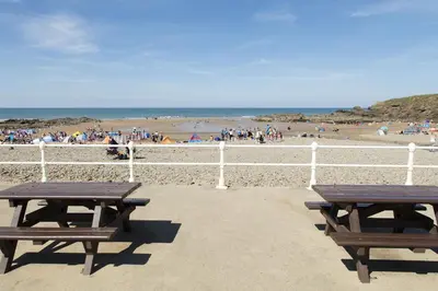 two picnic tables on a beach with a crowd of people at Hazeldene amazing sea and countryside views in Crackington Haven
