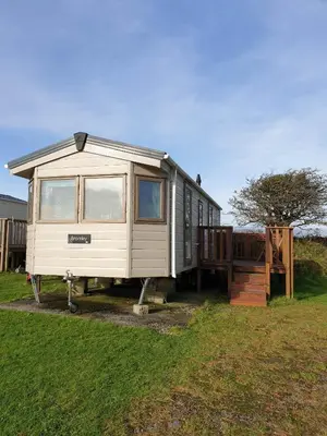a white tiny house parked in a yard at Static Caravan 9 in Lansallos