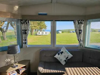a living room with a couch and two windows at Static Caravan 9 in Lansallos