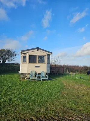 a tiny house with two chairs in a field at Static Caravan 10 in Lansallos
