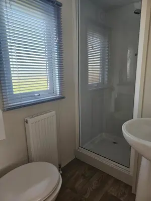a bathroom with a shower and a toilet and a sink at Static Caravan 10 in Lansallos