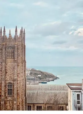 a large brick building with a tower next to the ocean at The White House Hotel in Newquay