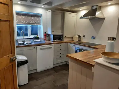 a kitchen with white cabinets and a wooden counter top at 2 Umfula Place in St Ives