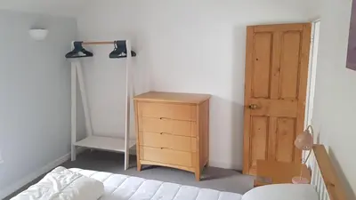a bedroom with a bed and a dresser and a door at 2 Umfula Place in St Ives