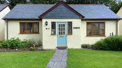 a small white house with a blue door at Inny Glade in Davidstow