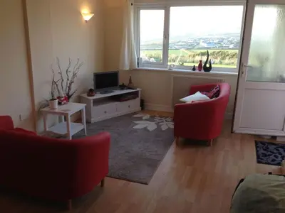 a living room with two red chairs and a television at Iluka in Widemouth Bay