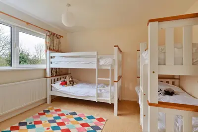 a bedroom with two bunk beds and a window at Goonrea in Looe