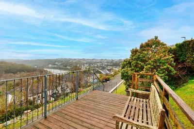 a wooden boardwalk with a bench on a hill at Goonrea in Looe