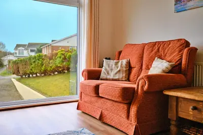 a orange chair in a living room with a window at Goonrea in Looe