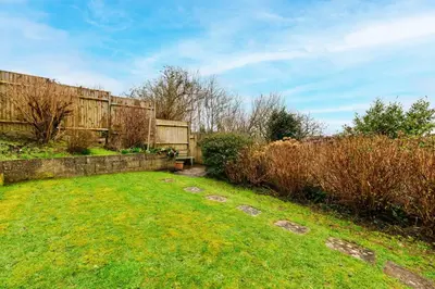 a backyard with a stone fence and a grass yard at Goonrea in Looe