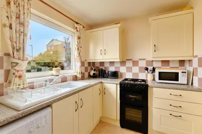 a kitchen with white cabinets and a sink and a window at Goonrea in Looe