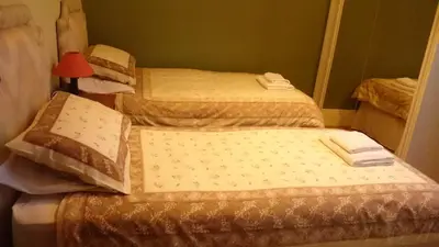 two twin beds in a room with a lamp at Bankside Bed & Breakfast in St Austell