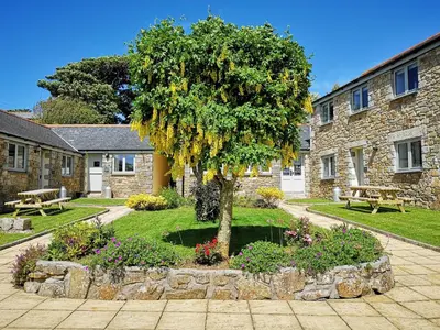 a tree in a garden next to a stone building at Ash in Scorrier