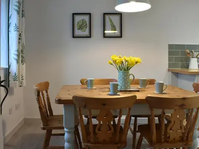 a wooden table with chairs and a vase of flowers at Ash in Scorrier