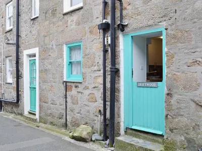 a stone building with a blue door and windows at Driftwood in St Ives
