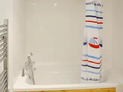 a bath tub with a shower curtain in a bathroom at Driftwood in St Ives