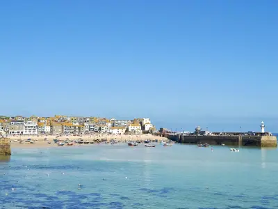 a beach with a group of boats in the water at Driftwood in St Ives