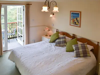 a bedroom with a bed and a balcony at Little Larnick in Looe