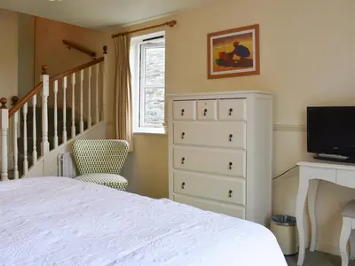 a bedroom with a bed and a dresser with a television at Little Larnick in Looe