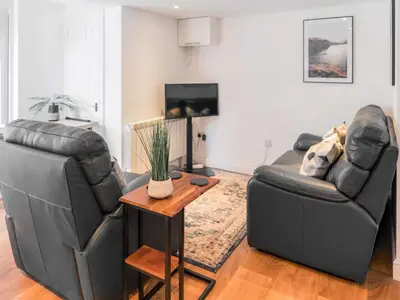 a living room with two leather couches and a table at The Pool House in Tywardreath