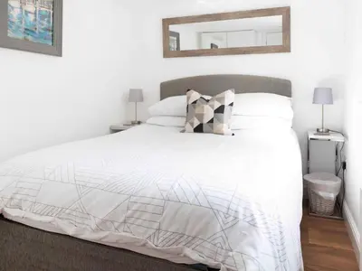 a bedroom with a white bed with a mirror on the wall at The Pool House in Tywardreath