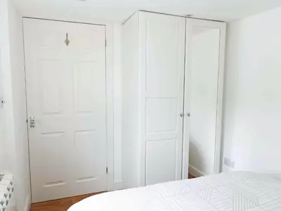 a white bedroom with white closet doors and a bed at The Pool House in Tywardreath