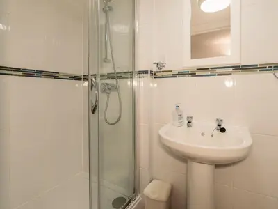 a white bathroom with a sink and a shower at The Pool House in Tywardreath
