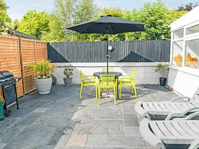 a patio with a table and chairs and an umbrella at The Pool House in Tywardreath