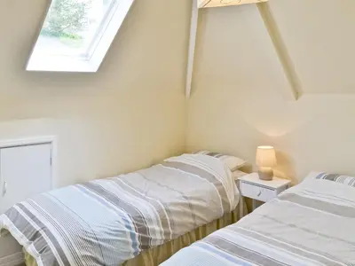 two beds in a room with a window at Watersmeet in Looe