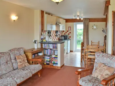 a living room with a couch and a table and a kitchen at Brambles in St. Agnes